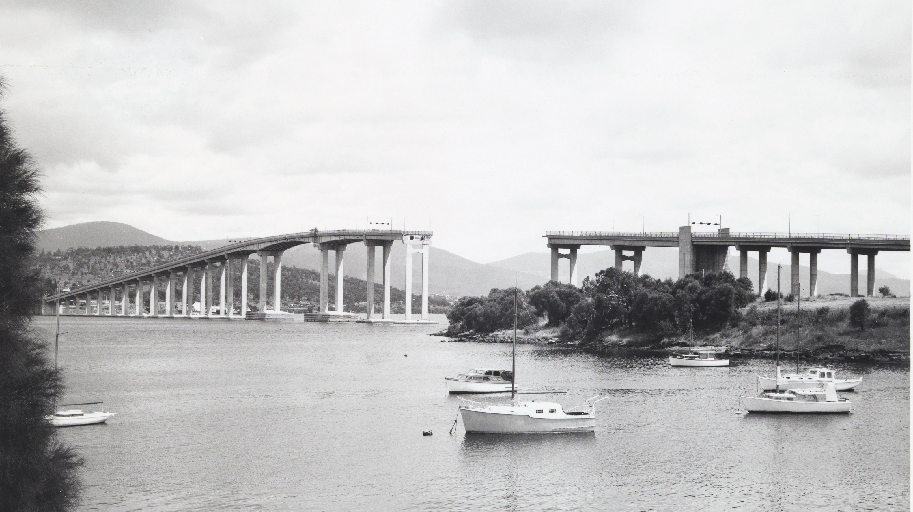 View_of_the_Tasman_Bridge_from_Kalatie_Road_Montague_Bay_looking_toward_the_Powder_Jetty_over_Cuthbertson's_Boat_shed_(1975)_(16200189861)